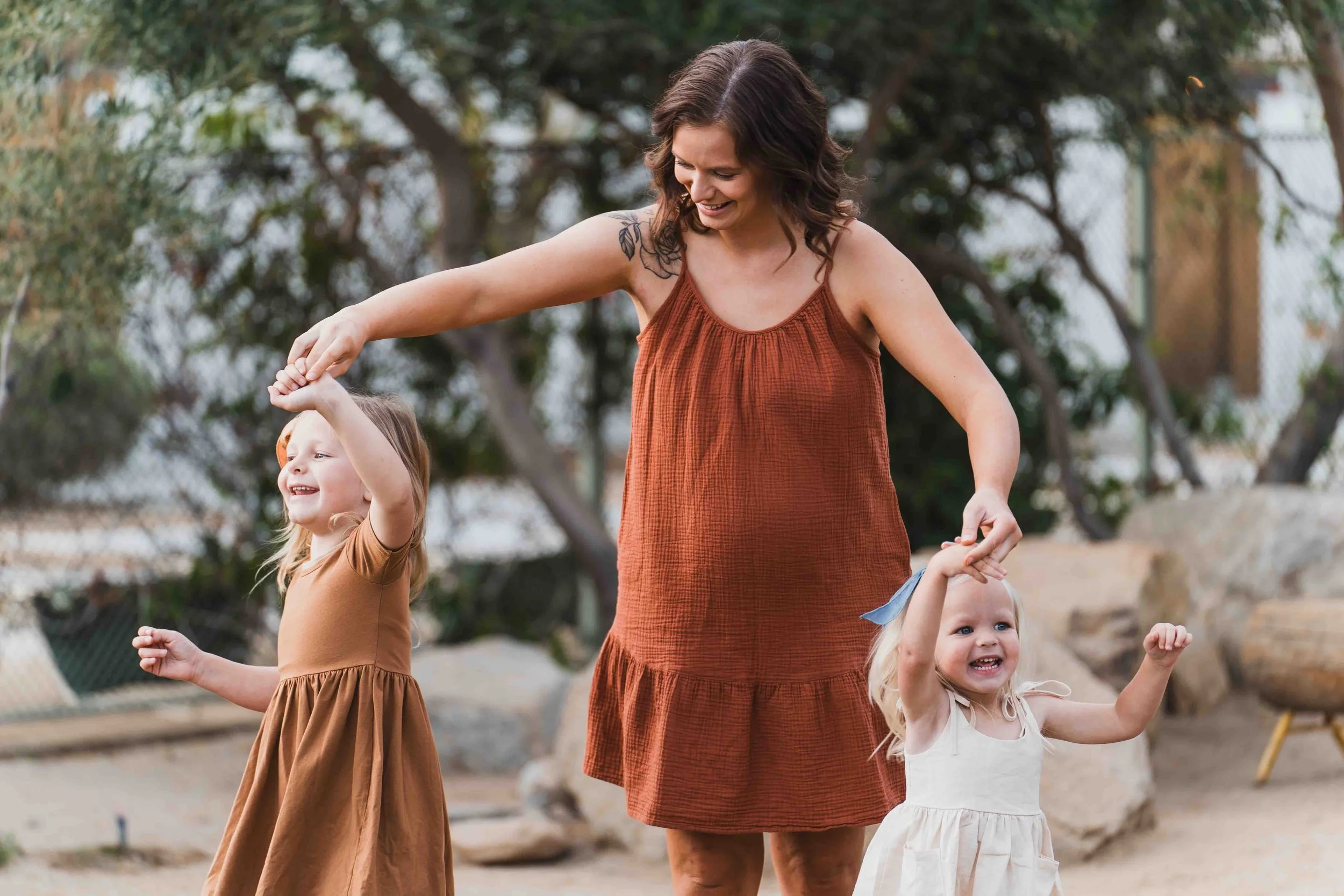 pregnant mom twirling two girls around, one in each hand