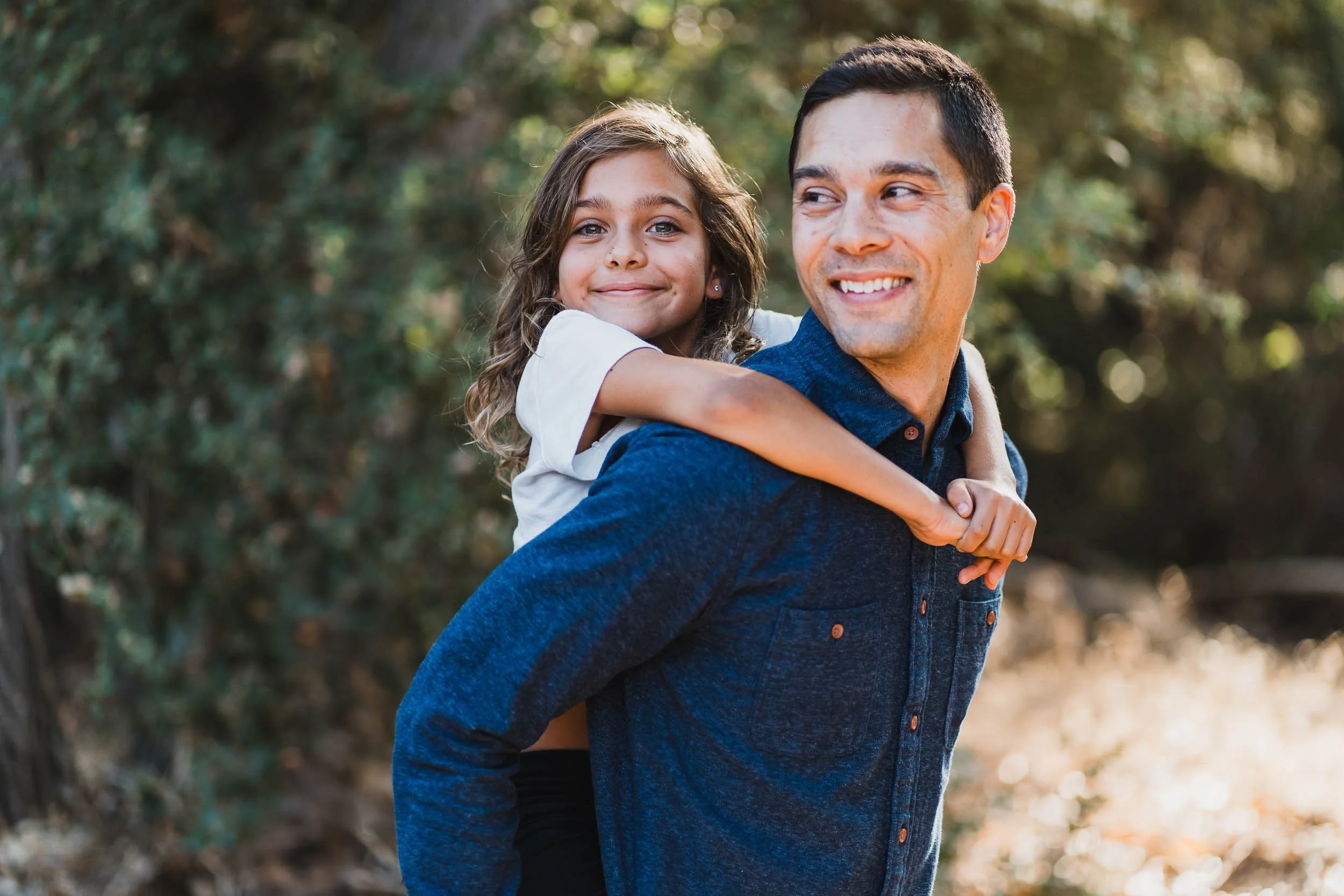 dad giving daughter a piggy back ride at park