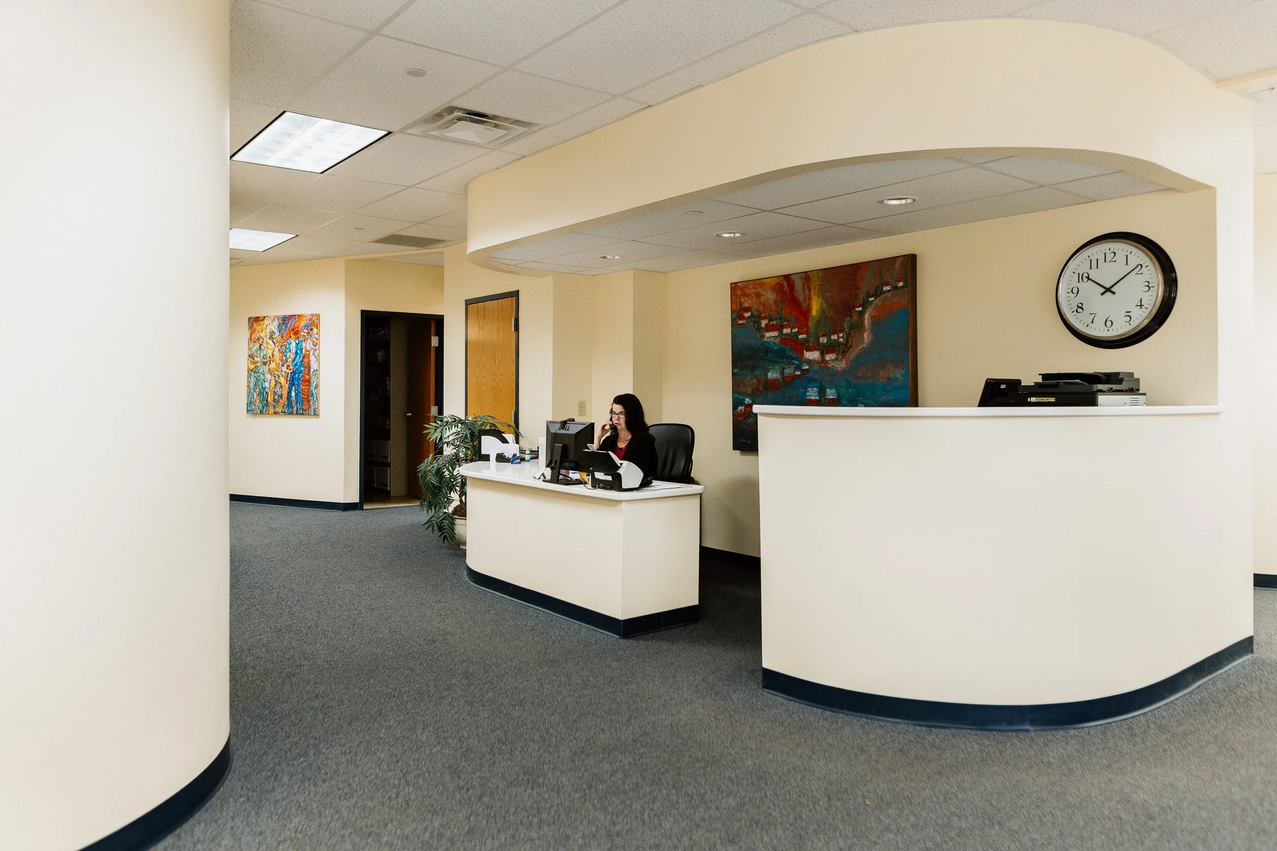 The EMC office front desk area is shown with Marcia on the phone
