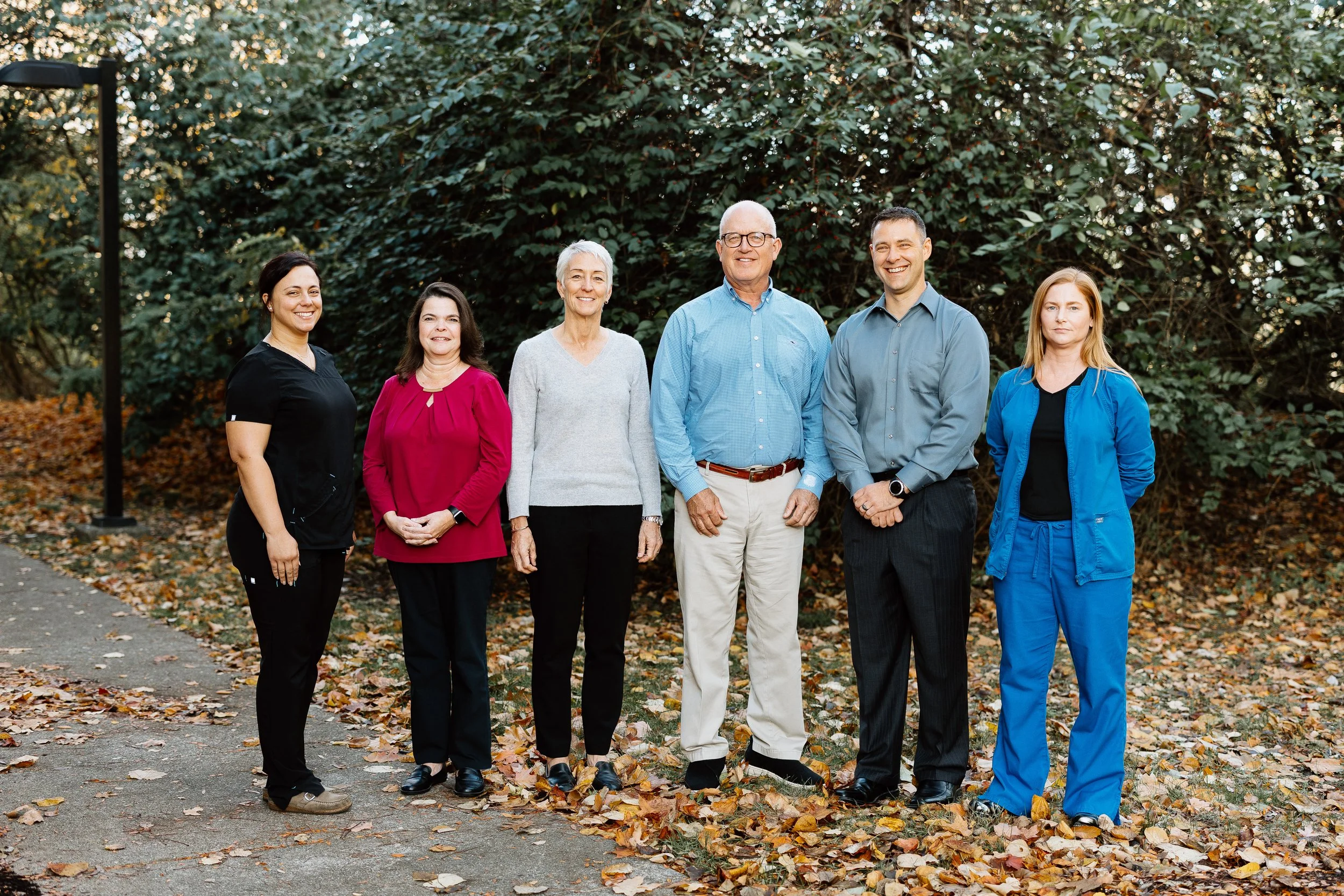 The EMC Ohio team smiles for the camera outdoors against a tree-lined background