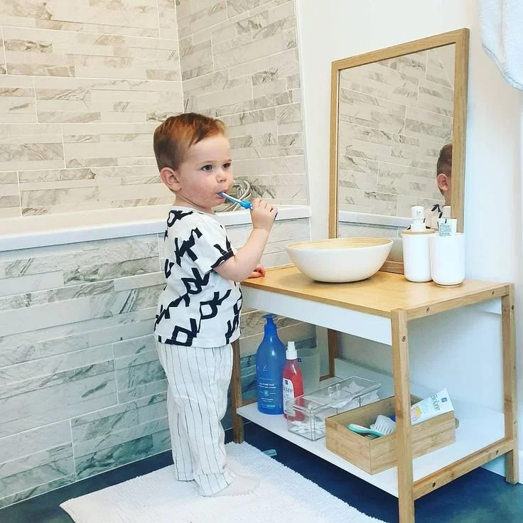Little boy brushing teeth in self care station in bathroom