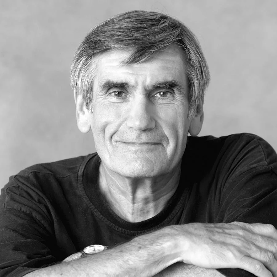 Dr. Marshall Rosenberg souriant portant un pull noir, posé sur ses avant-bras.