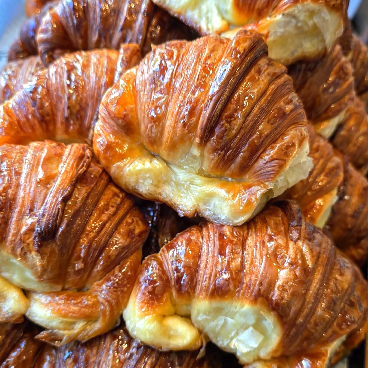 Close-up of several baked croissants with a golden-brown, flaky exterior.
