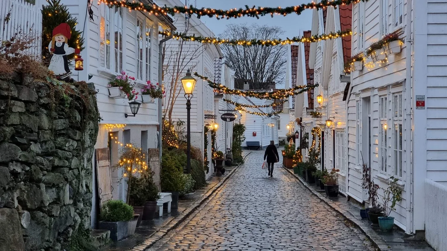 Cobbled street lined with white wooden houses and festive lights in old Stavanger