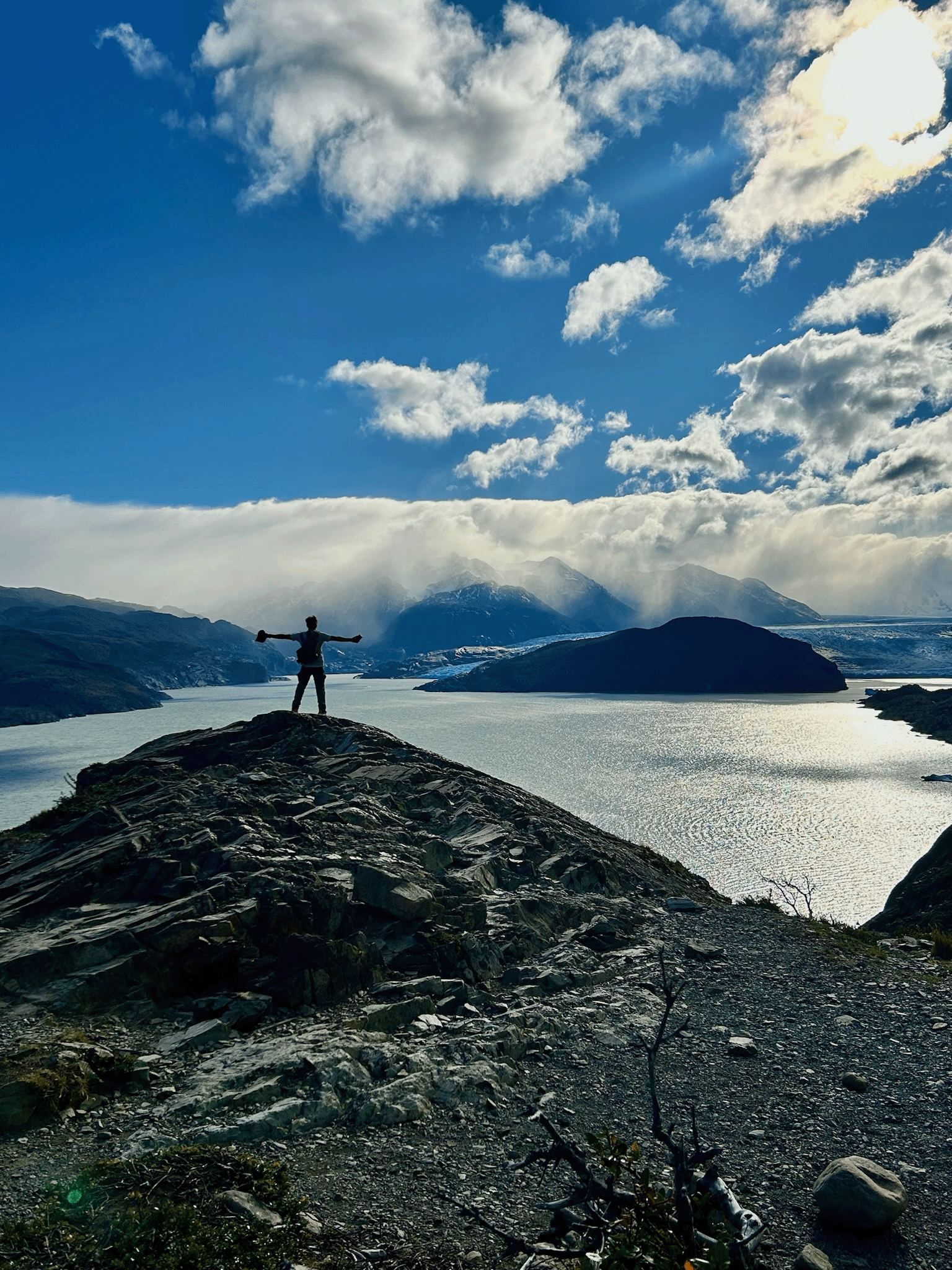 Hiker with arms raised above a lake in Torres del Paine National Park, Patagonia