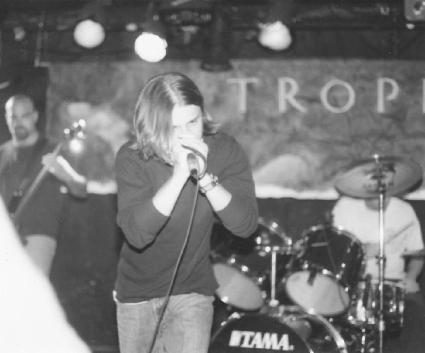 Man singing on stage with a band behind him