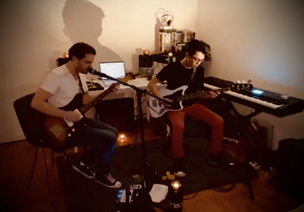 Two men seated and performing music in an apartment