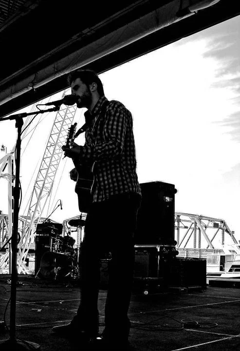 Man with guitar performing on stage at Steel Bridge Song festival