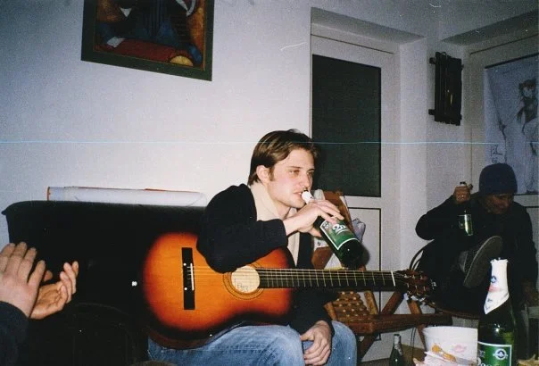 Man drinking a beer after performing a song on acoustic guitar in an apartment in Zhuzhou, China