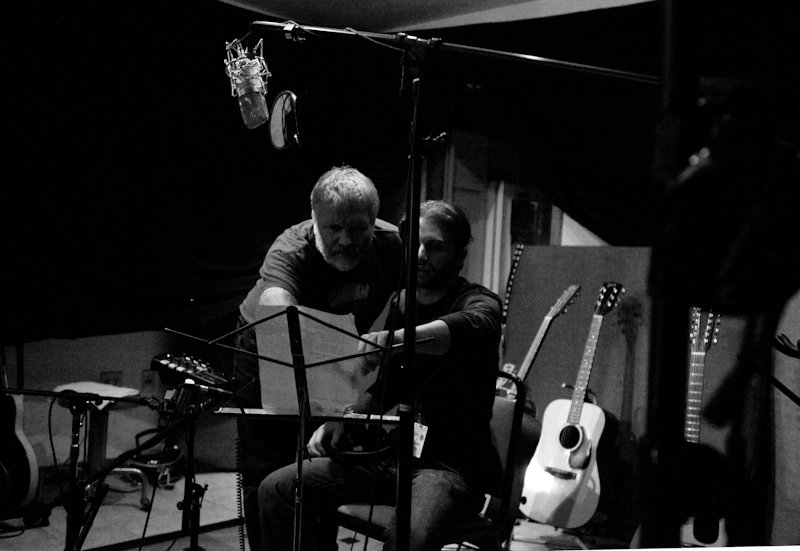Two men pointing at music stand in a recording studio