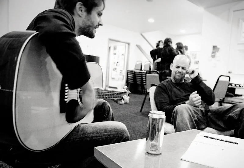 Man playing guitar while another listens