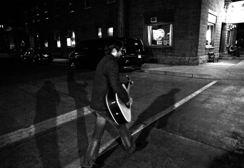 Man walking on street with acoustic guitar