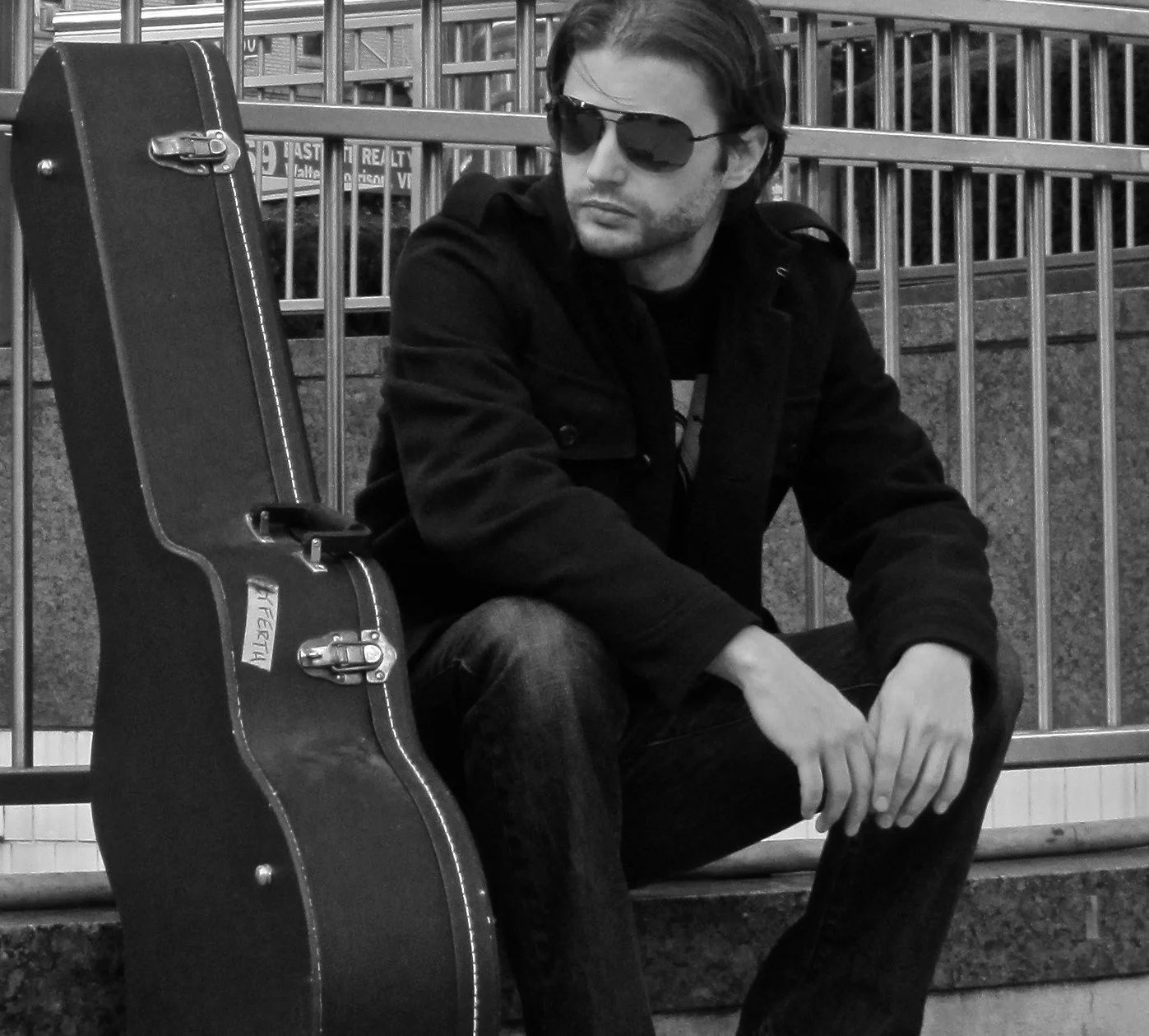 Man sitting next to guitar case in New York City