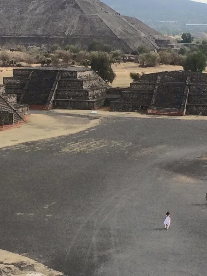Woman in white dress walking across the ground in Teotihuacan, Mexico
