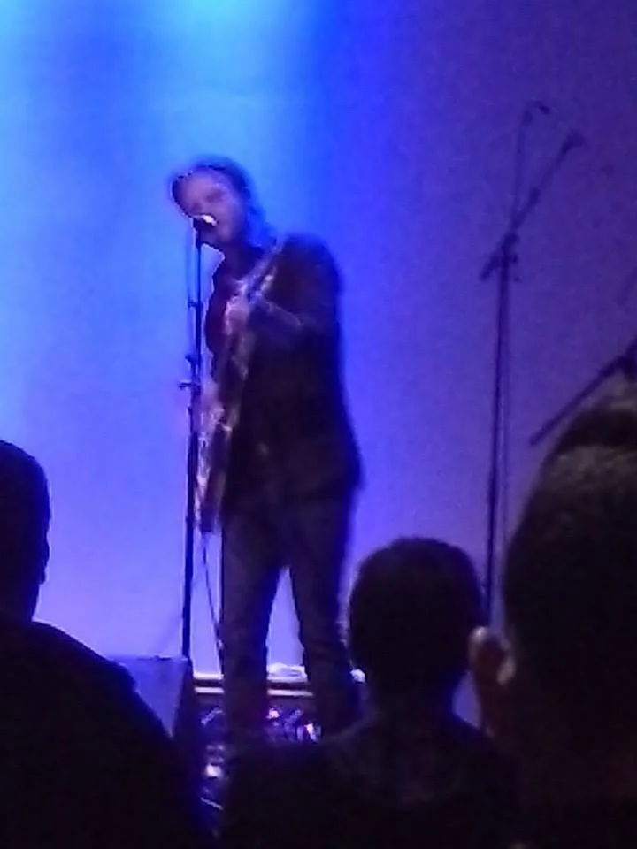 Man performing guitar and singing on stage