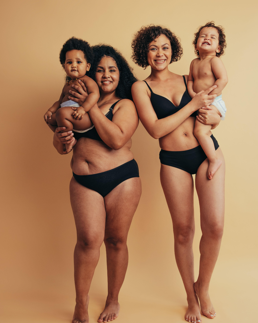 two postpartum women holding children
