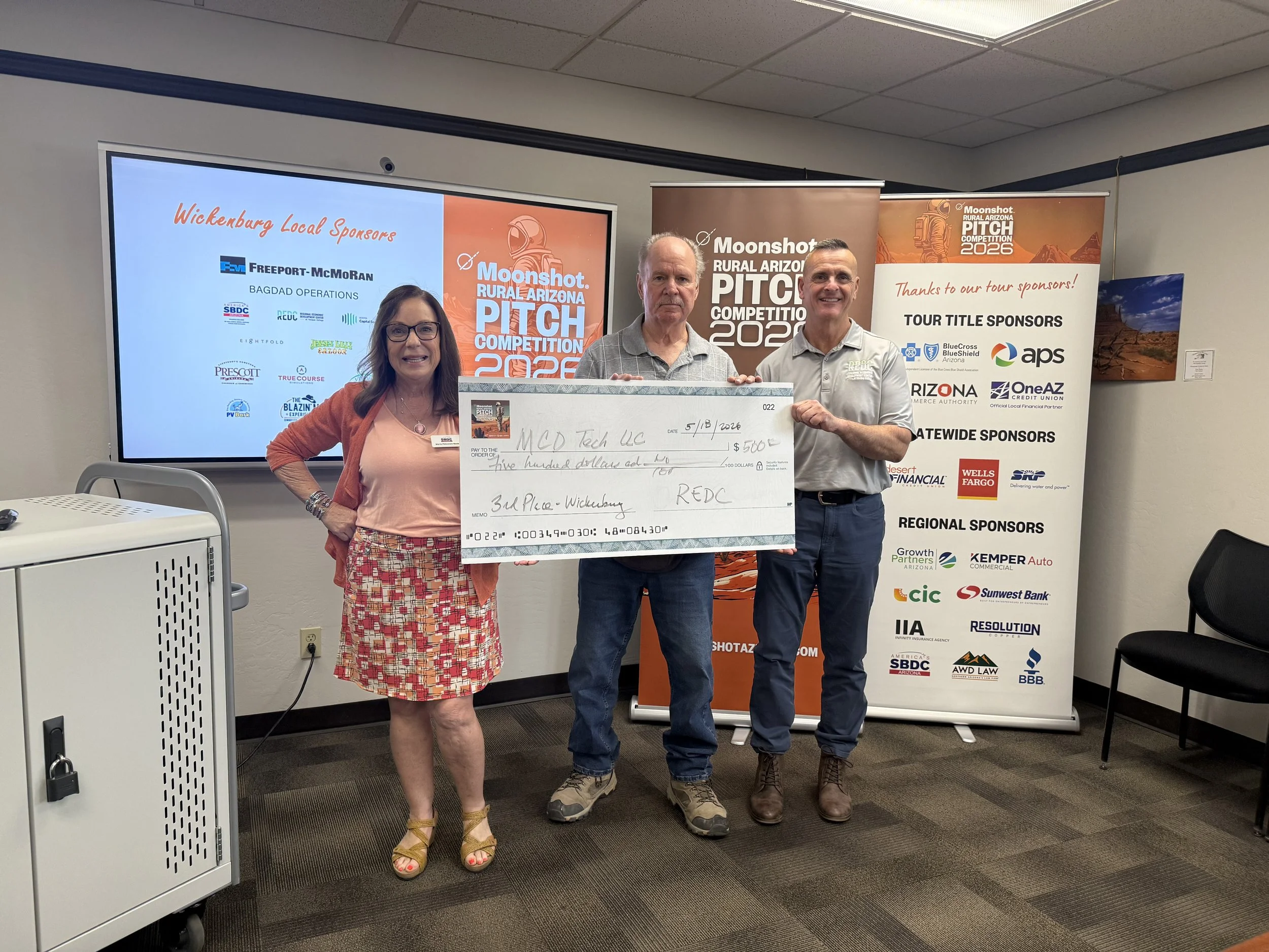 three people holding a check