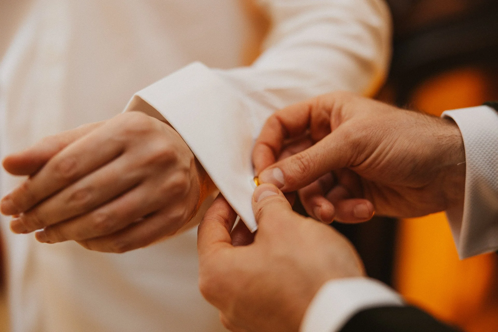 Detailaufnahme der Hände des Bräutigams beim Anziehen während des Getting Ready der Winterhochzeit.
