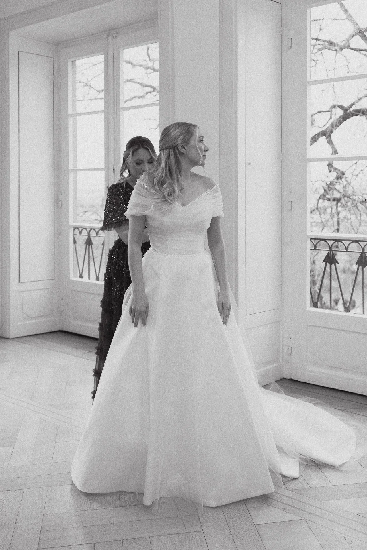 Schwarzweißaufnahme der Braut im Brautkleid in einem lichtdurchfluteten Raum des Klosterguts Besselich.
