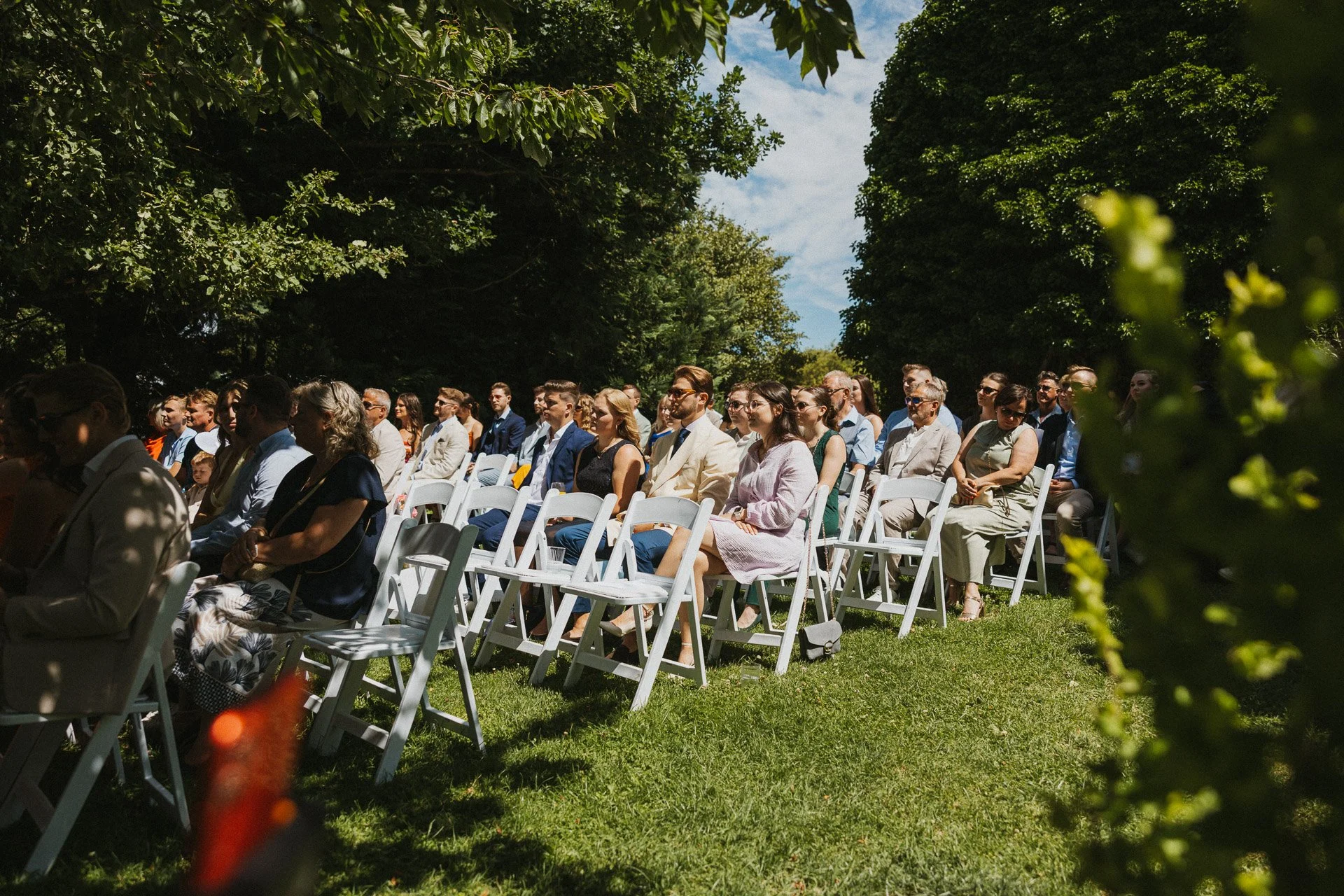 Hochzeitsgäste verfolgen die freie Trauung im Grünen.
