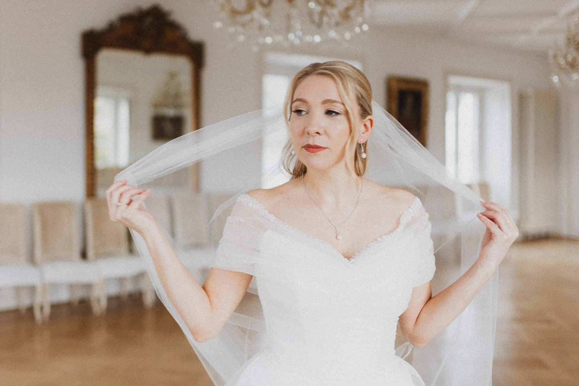 Die Braut Elisabeth mit Schleier während eines ruhigen Moments der Hochzeitsvorbereitungen.
