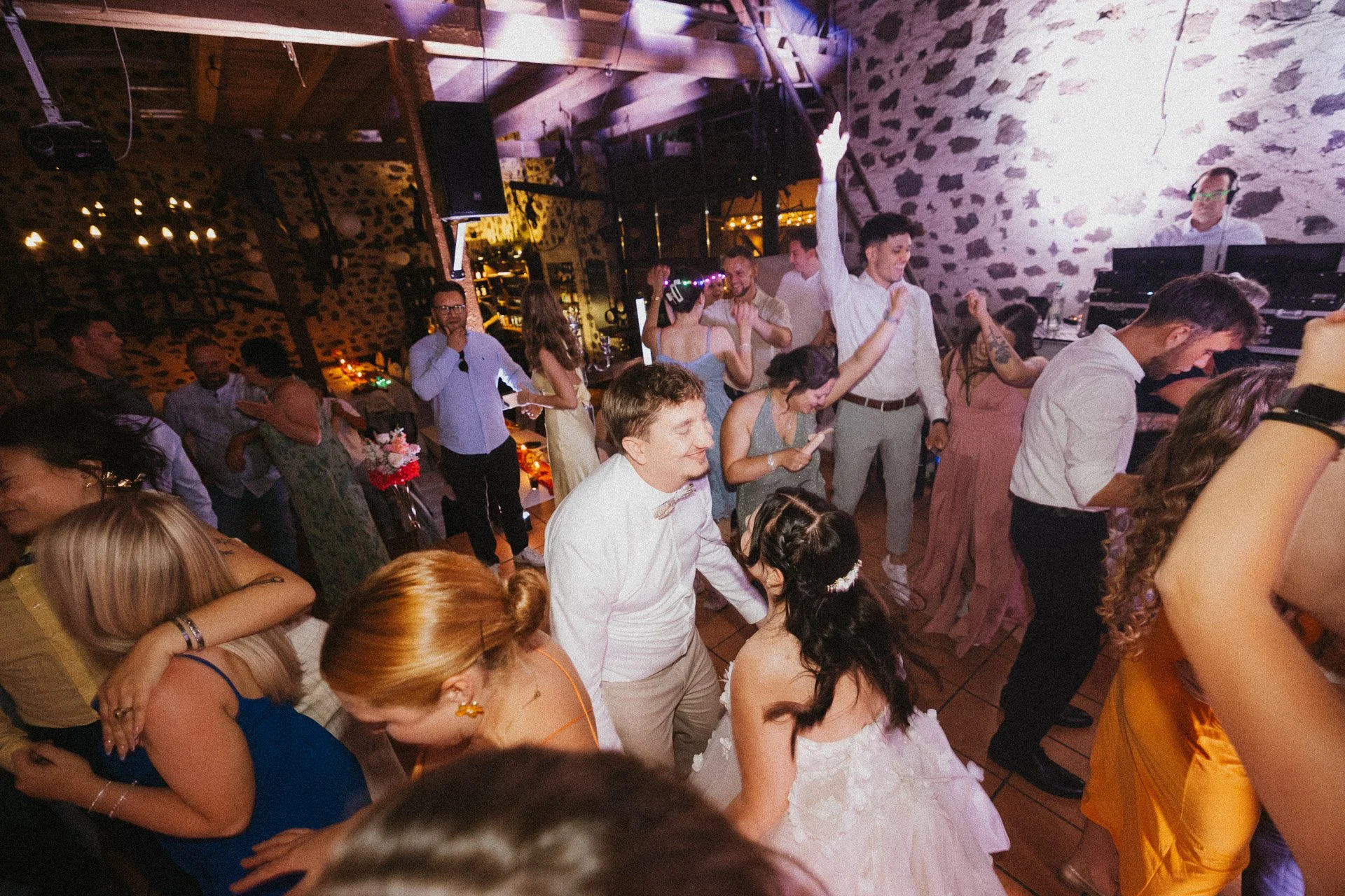 Hochzeitsgäste feiern ausgelassen auf der Tanzfläche am Abend.