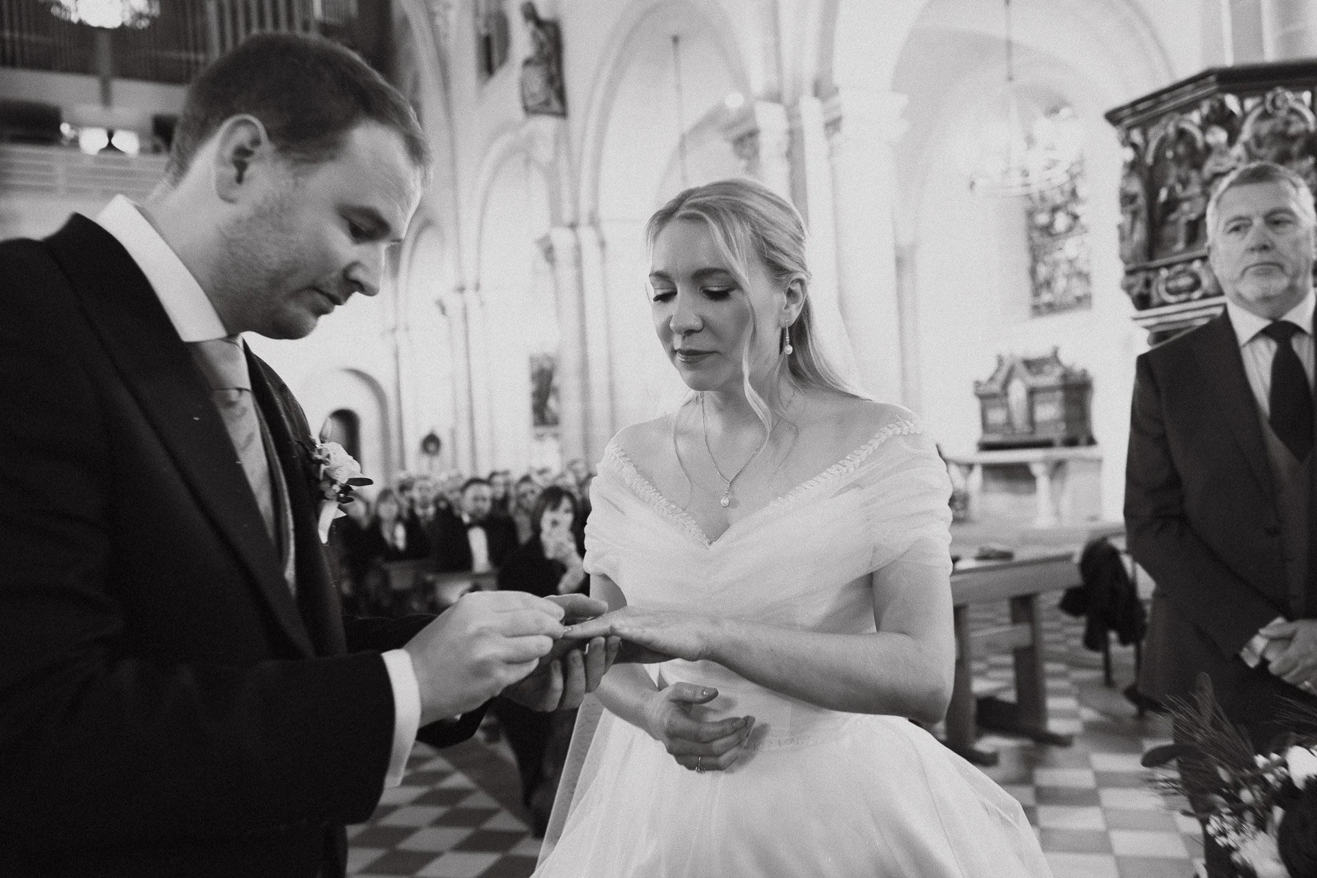 Schwarzweißaufnahme des Ringtausches während der kirchlichen Trauung.
