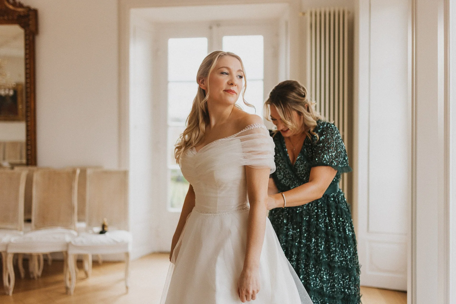 Moment zwischen Elisabeth und einer Begleiterin beim Anziehen des Brautkleids im Klostergut Besselich.
