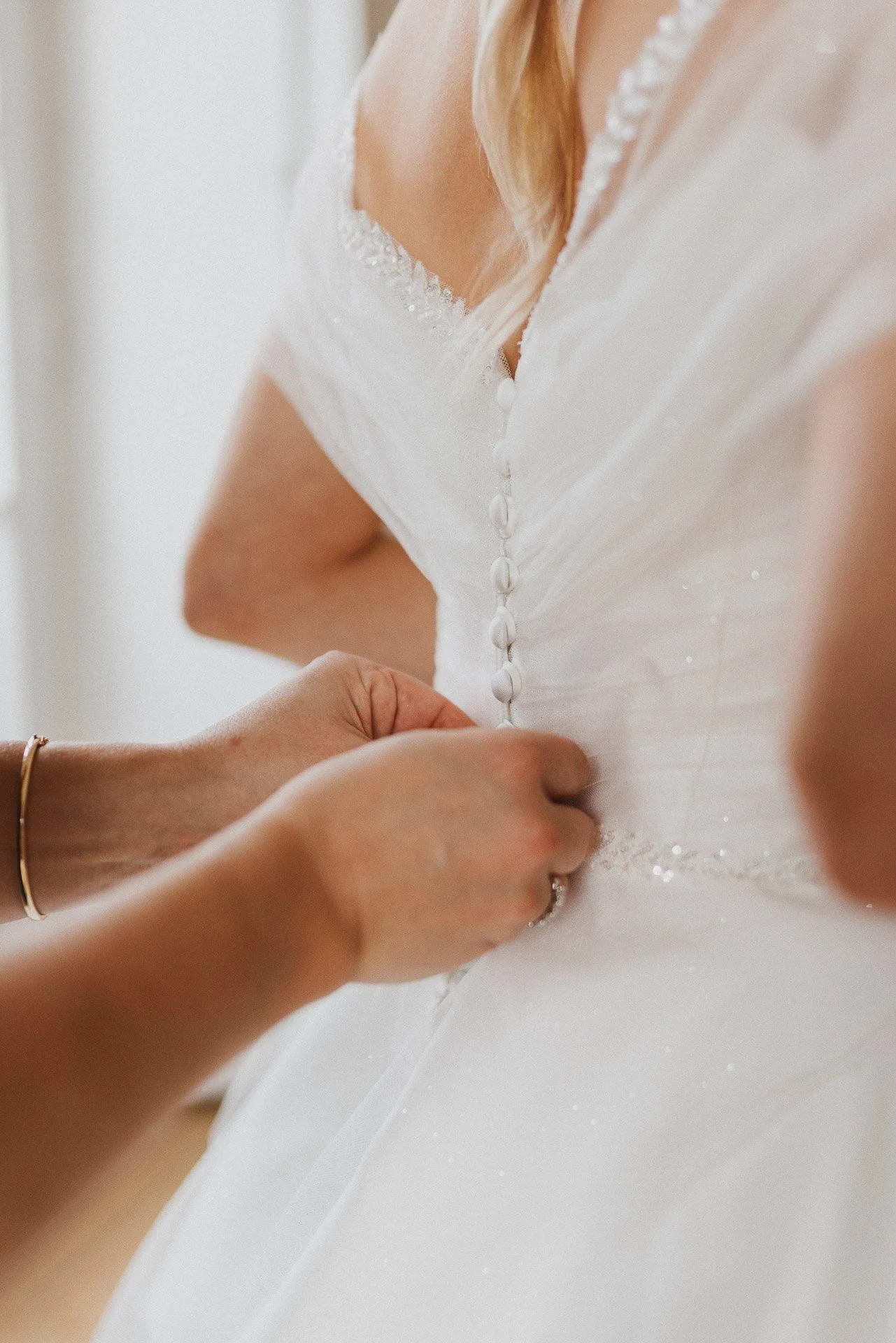 Detailaufnahme beim Schließen des Brautkleids während des Getting Ready der Winterhochzeit.
