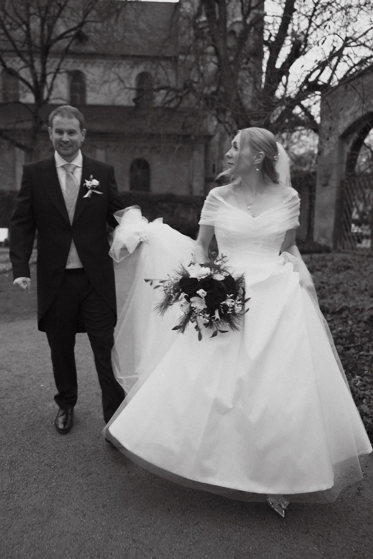 Schwarzweißaufnahme des Brautpaares beim gemeinsamen Auszug nach der Trauung.
