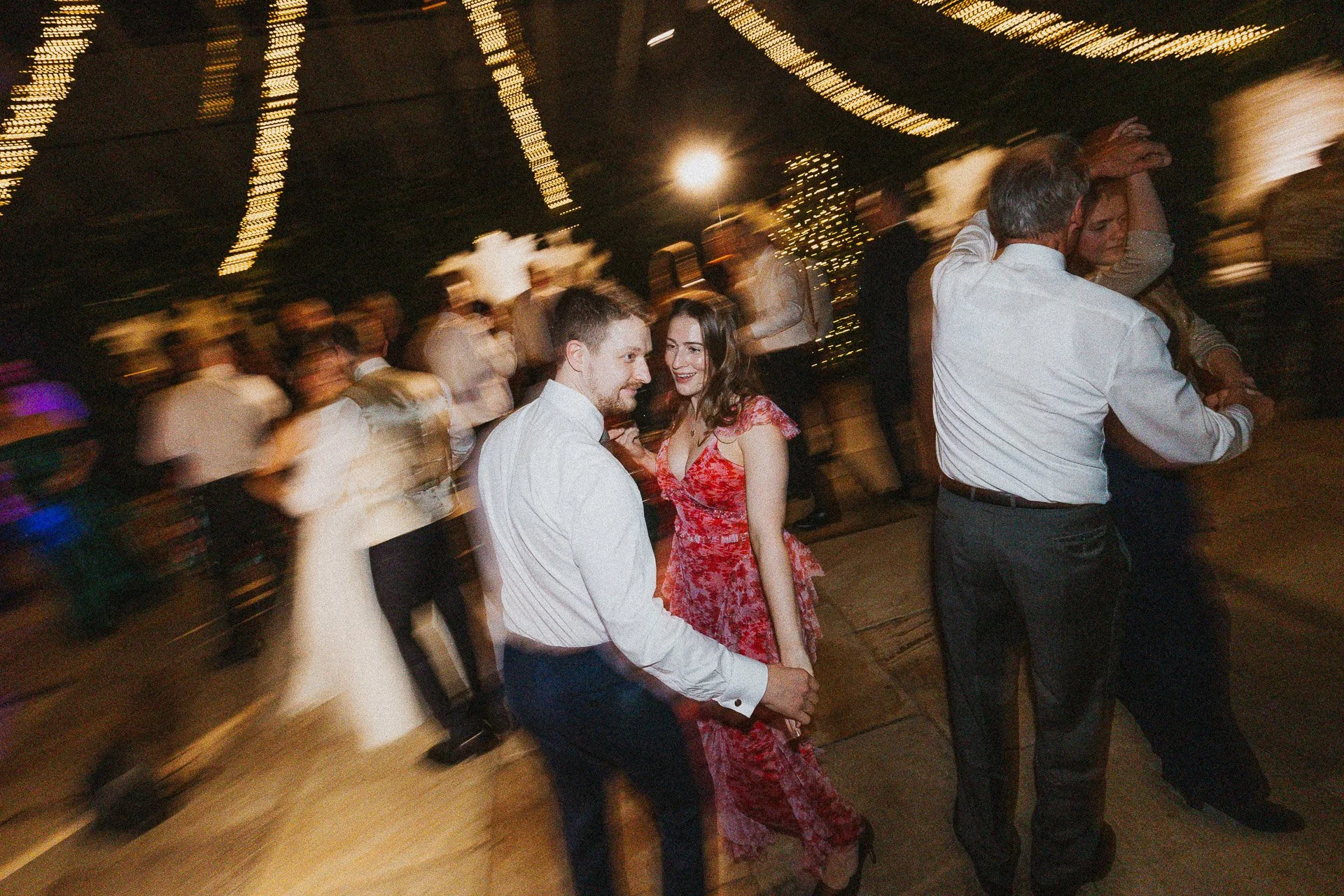 Hochzeitsgäste tanzen ausgelassen auf der Tanzfläche am Abend, eingefangen als dynamischer Moment der Hochzeitsreportage