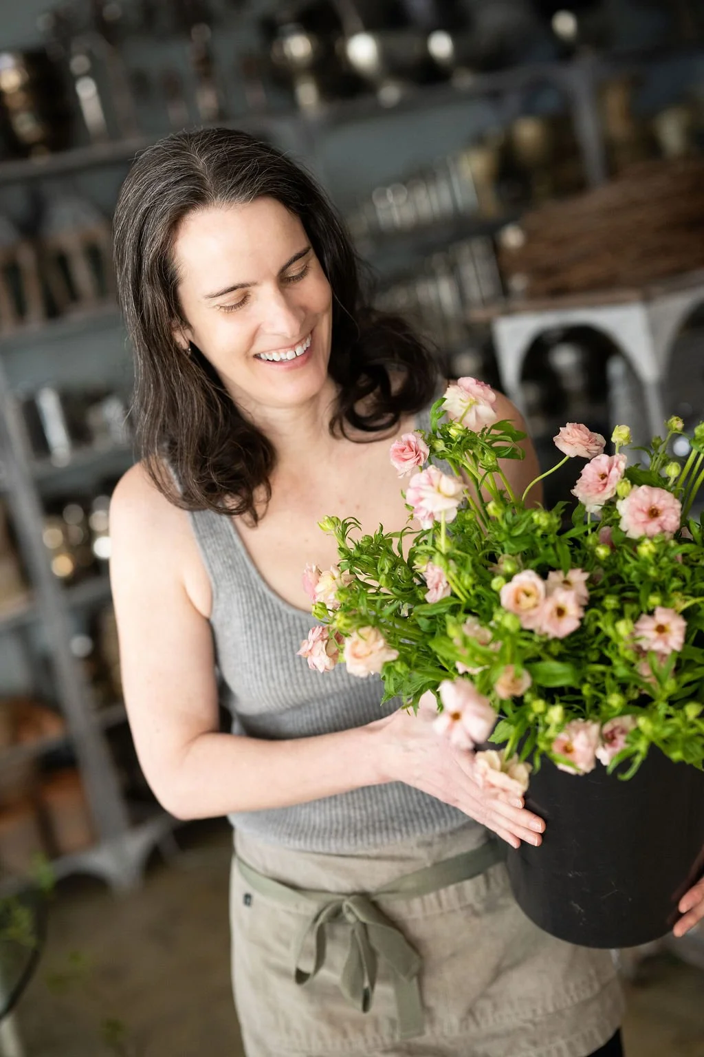 Woman holding a large bouquet of mixed pink and white flowers in a floral shop.