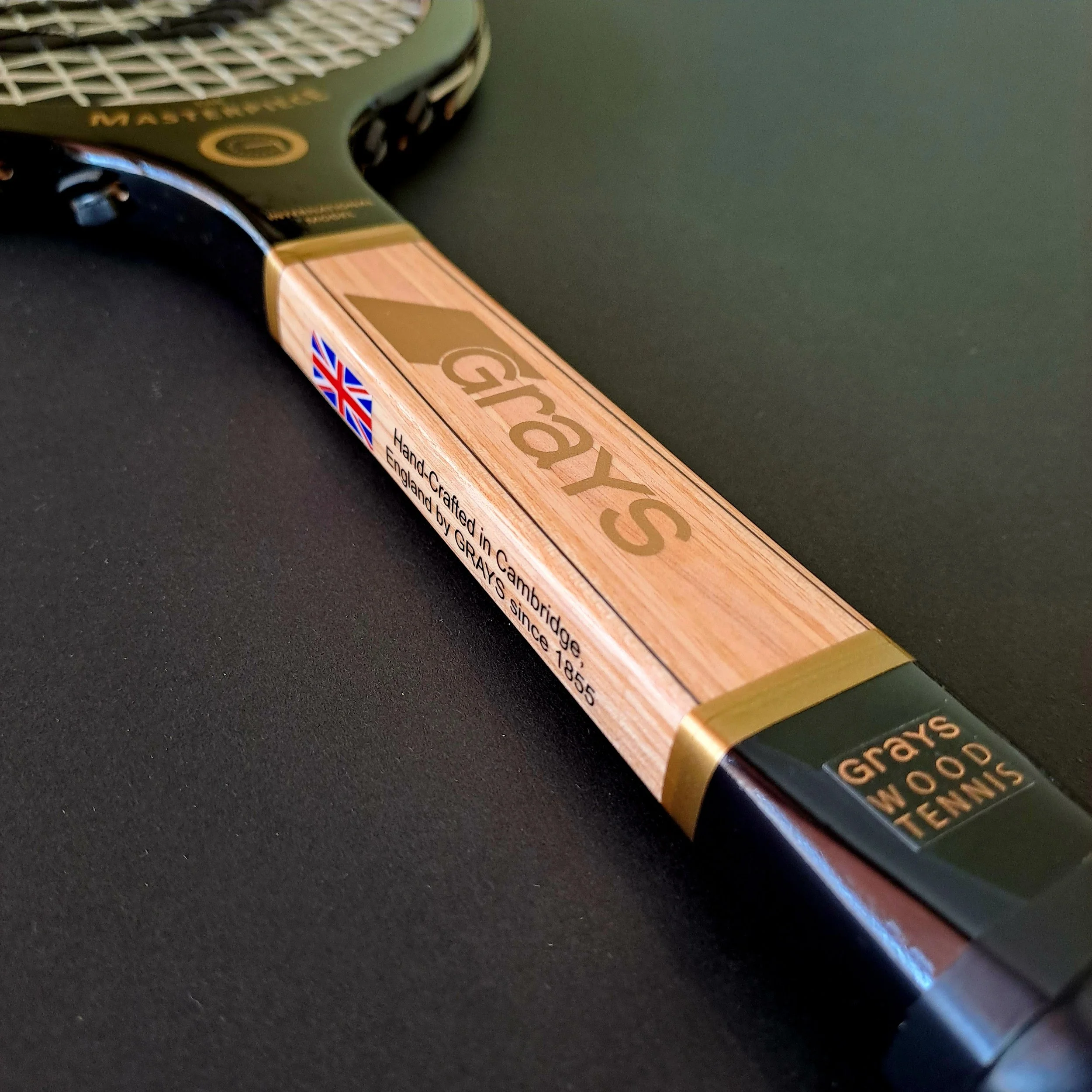 angled view of shaft and throat of racket against a black background