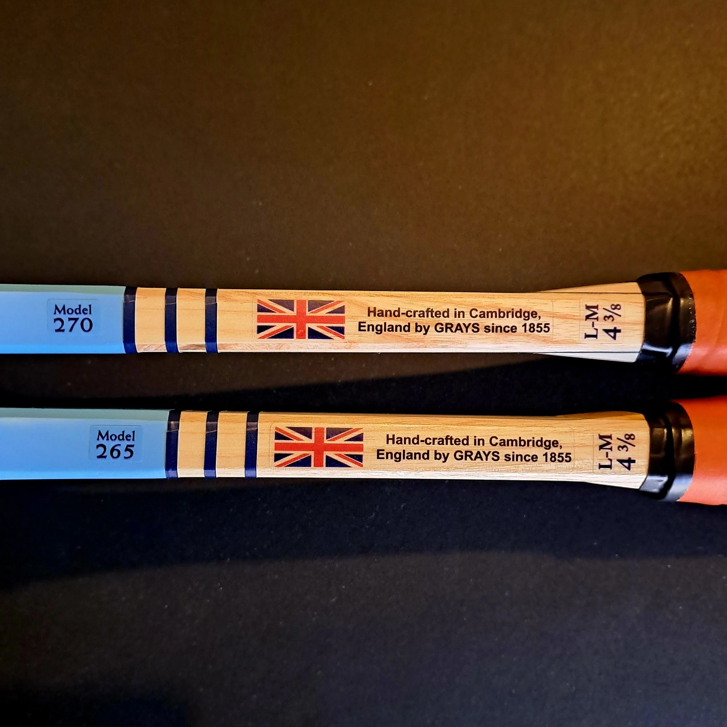 Full length side shaft views of two Grays Eco-Blue rackets against a black background