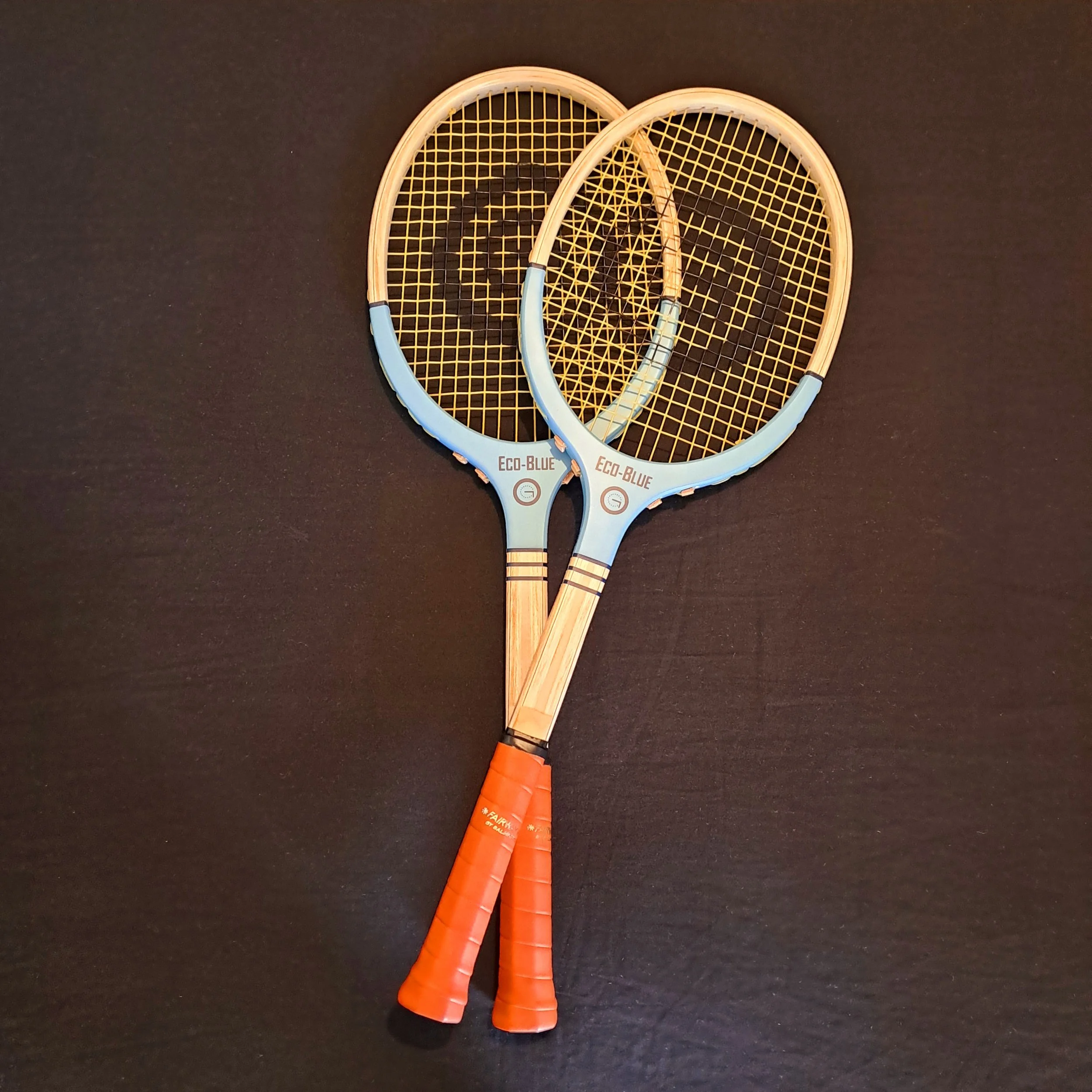 tw Grays Eco-Blue rackets slightly crossed against a black background