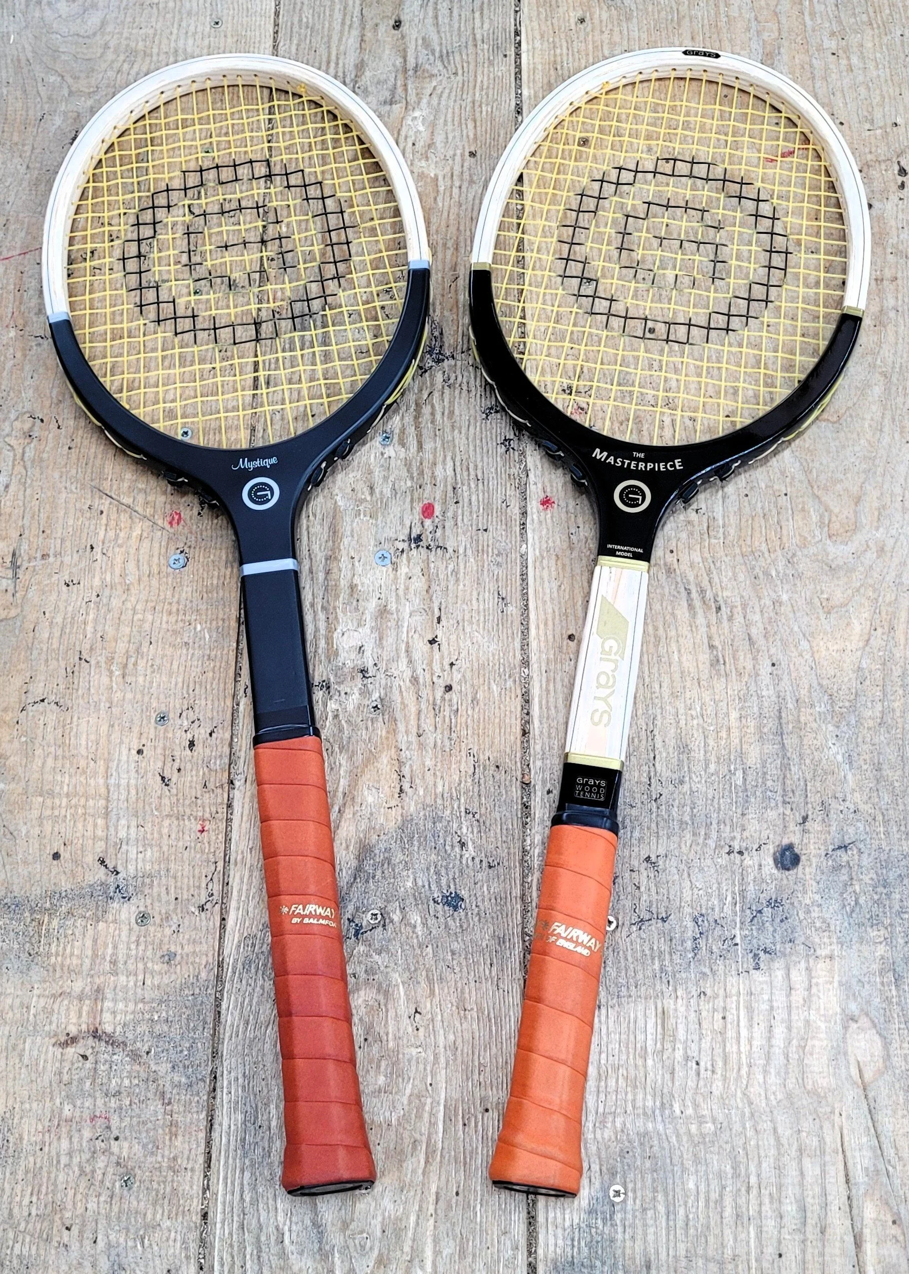 Two Grays rackets side by side resting on a timber surface.