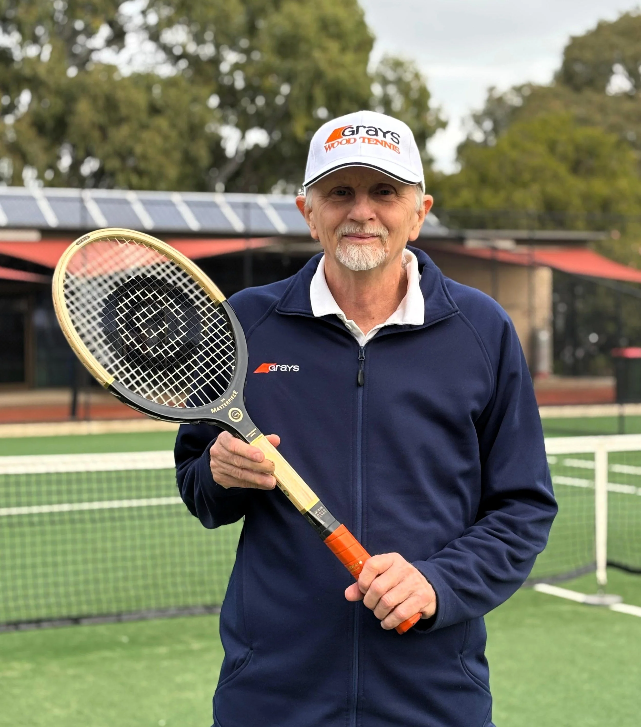 Stephen Murphy on a tennis court holding a Grays wooden racket.