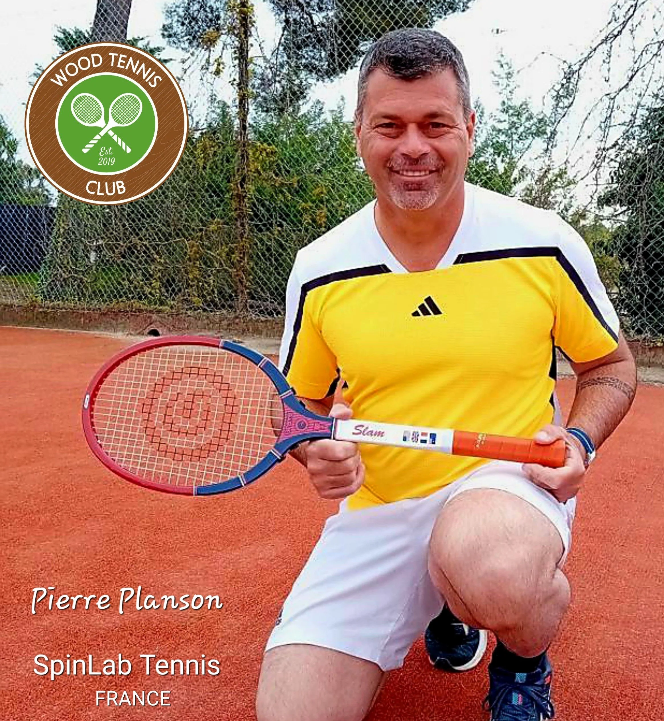 Coach Pierre Planson on a clay court showing his Grays Slam wooden racket.