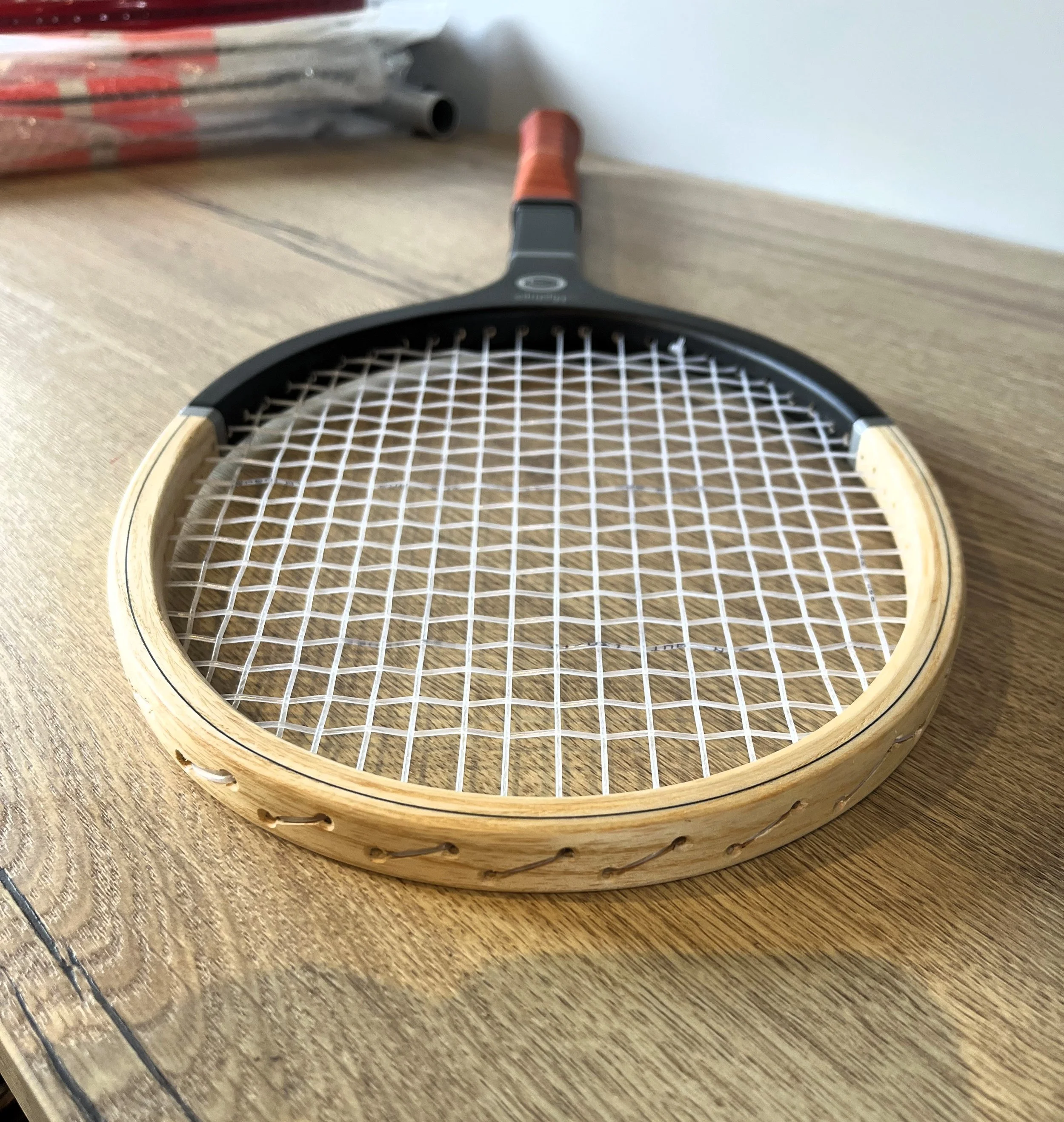 A strung Mystique racket laying on a wooden table.