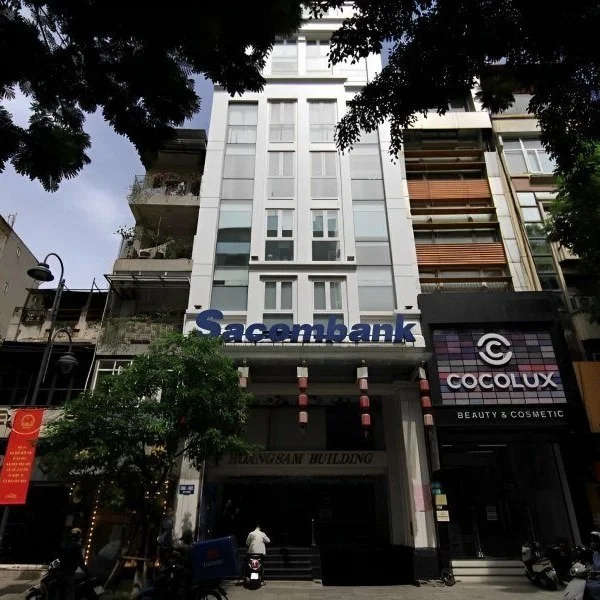 AGS ACCOUNTING HANOI OFFICE.
Front view of a building with Sacombank and Cocolux Beauty & Cosmetic signs, featuring modern architecture and trees along the street.