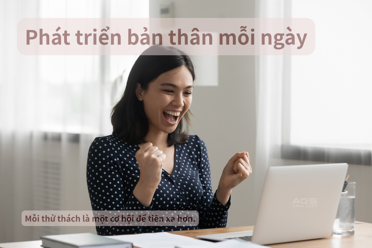 A woman celebrating success while sitting in front of a laptop with a glass of water on a desk in a bright room.