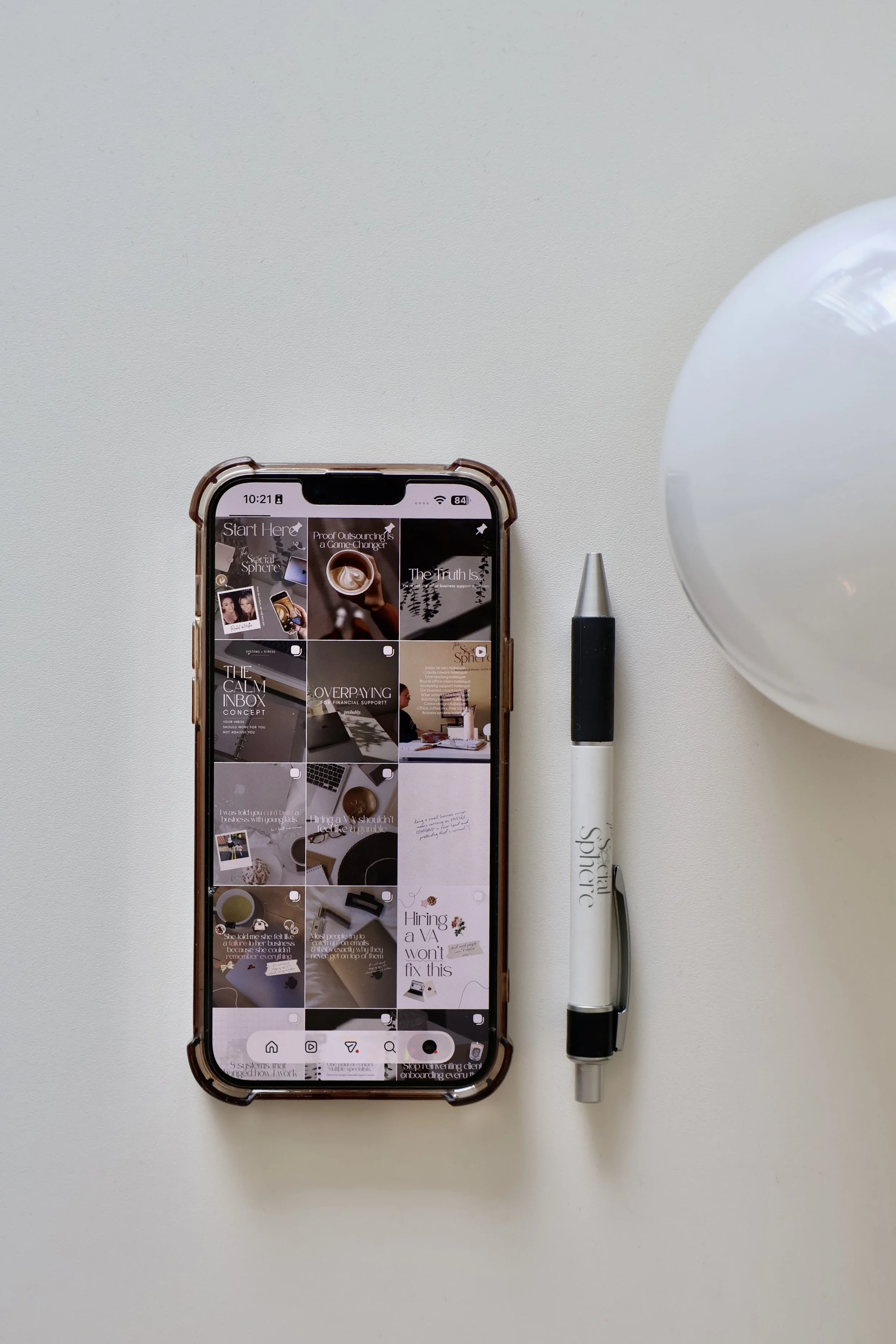 a phone showing the social sphere agency instagram and a branded pen with a globe light