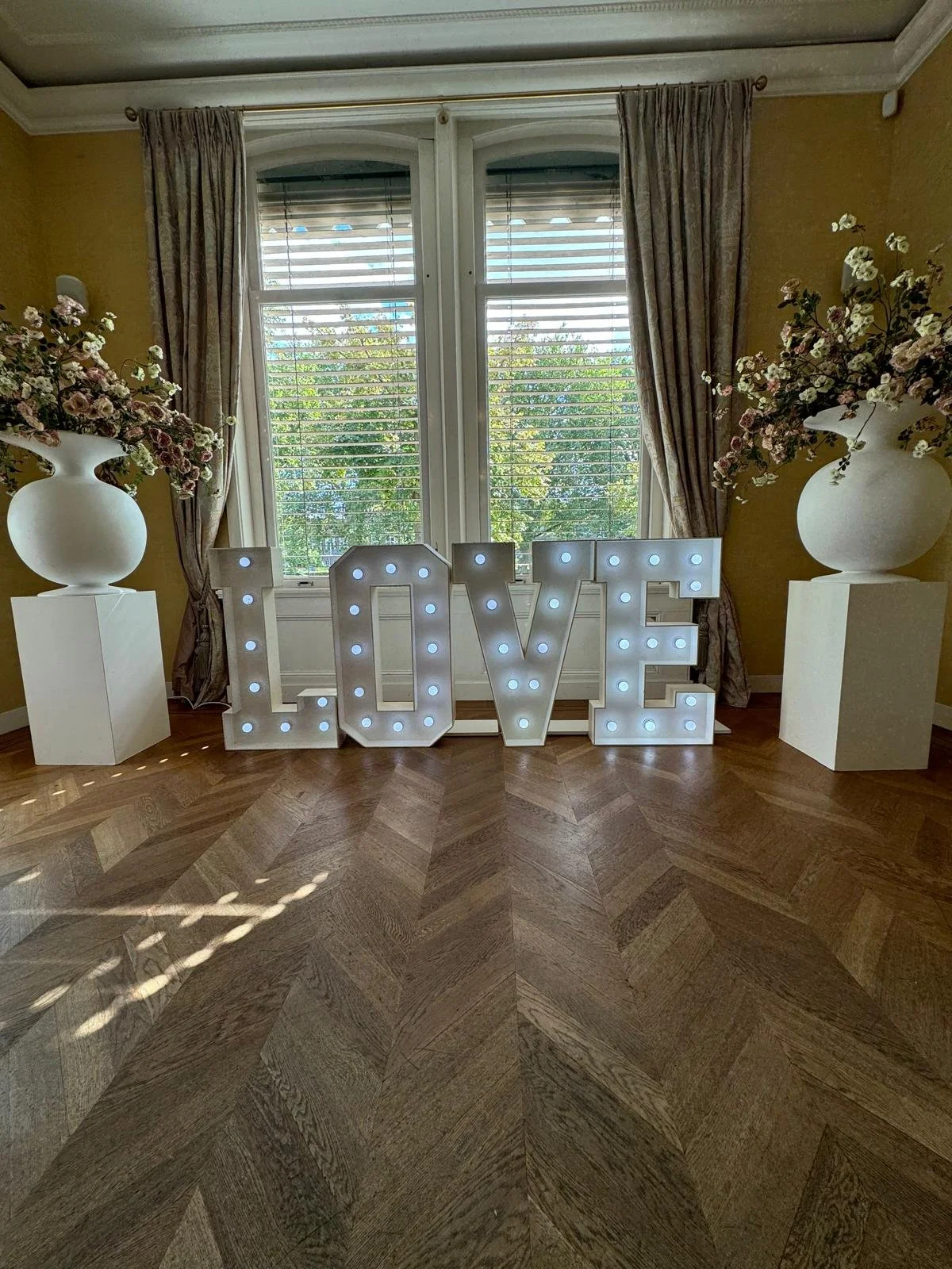 Verlichte letters die het woord 'LOVE' vormen in een donkere buitenomgeving.