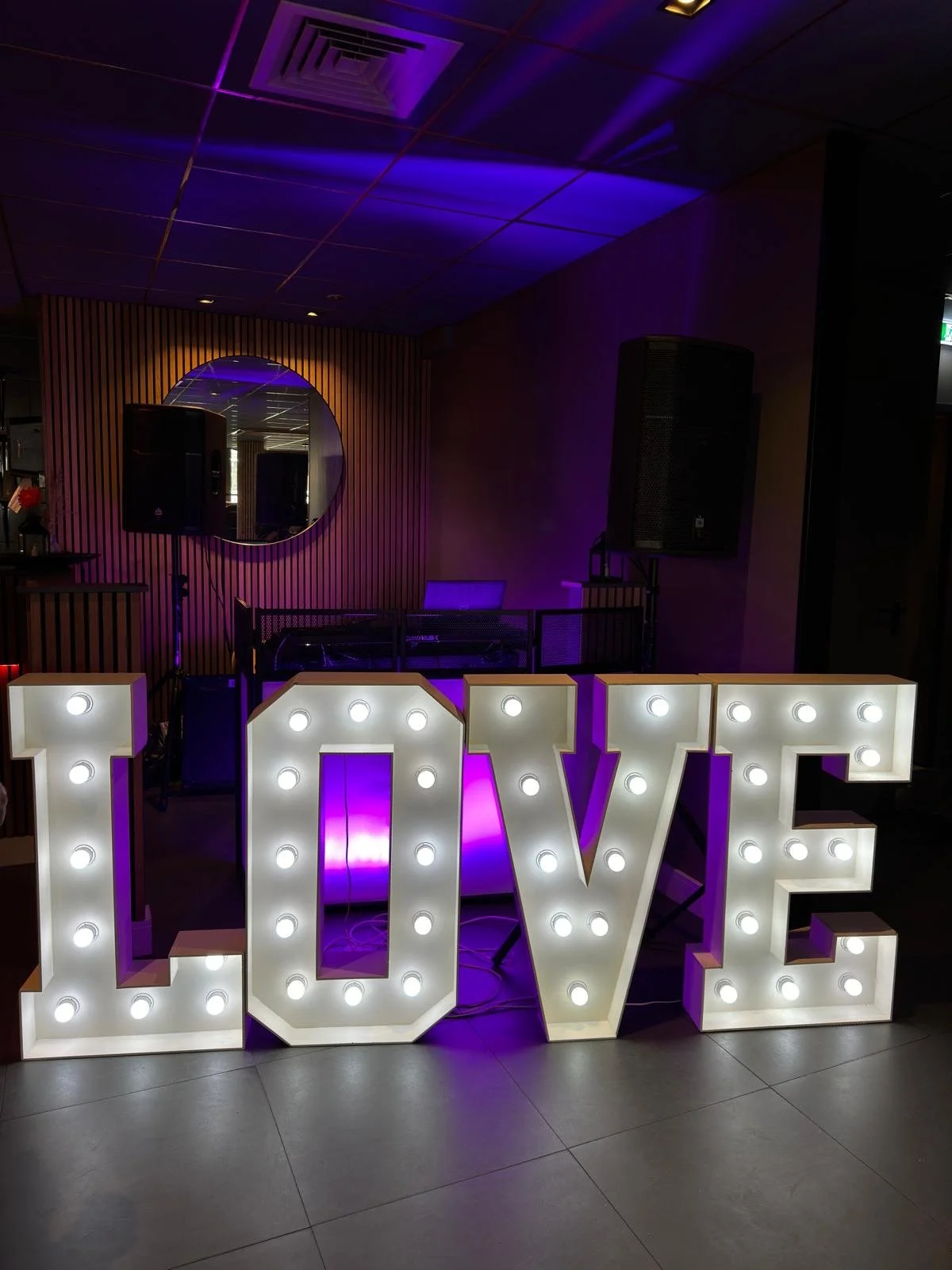 Grote verlichte letters die het woord LOVE vormen, met paarse verlichting op de achtergrond.