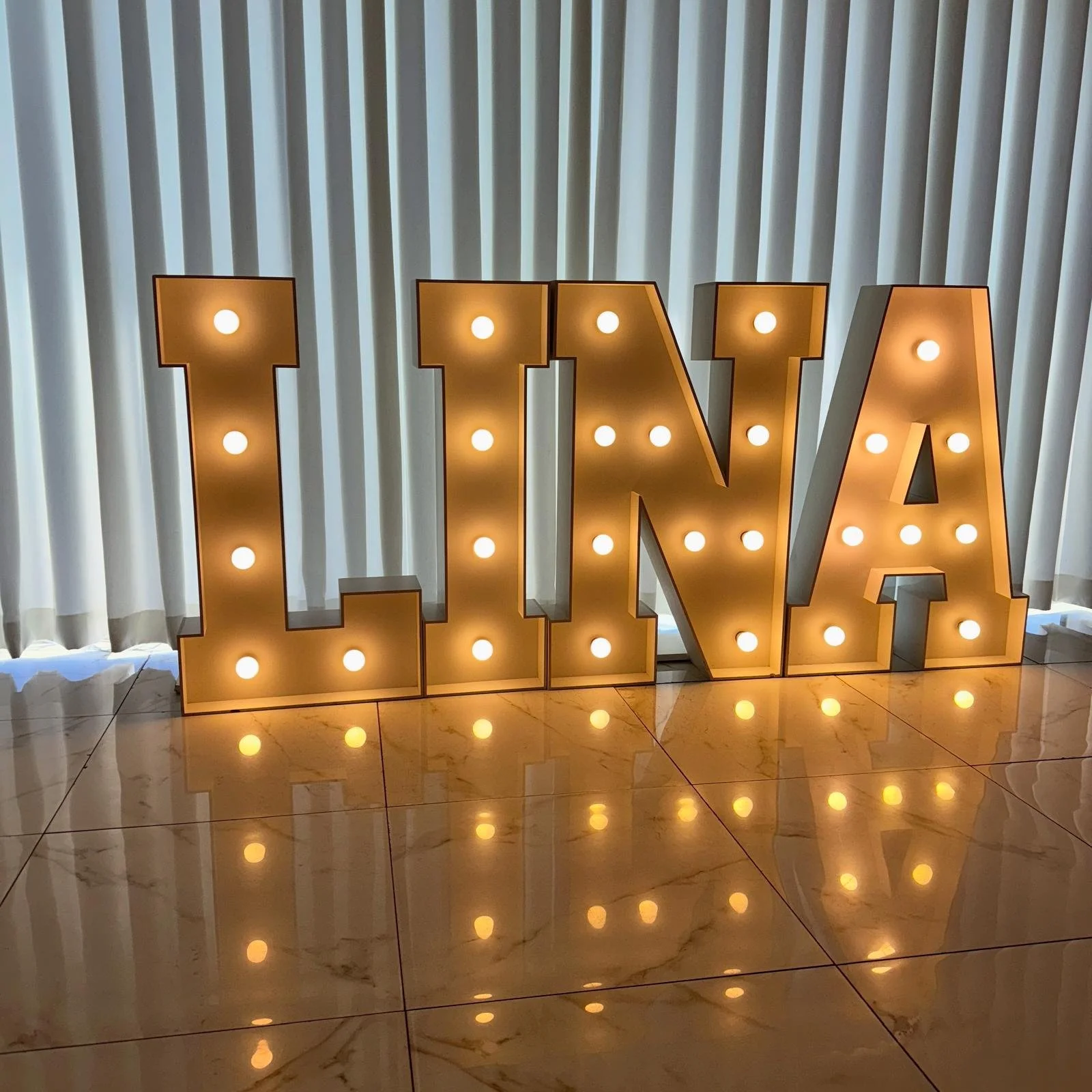 Verlichte letters die het woord 'BABY' vormen, omgeven door ballonnen.