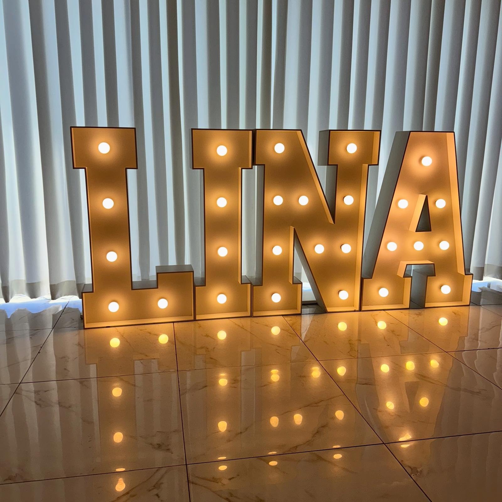 Verlichte letters die het woord 'BRIDE' spellen op gras bij een gebouw.