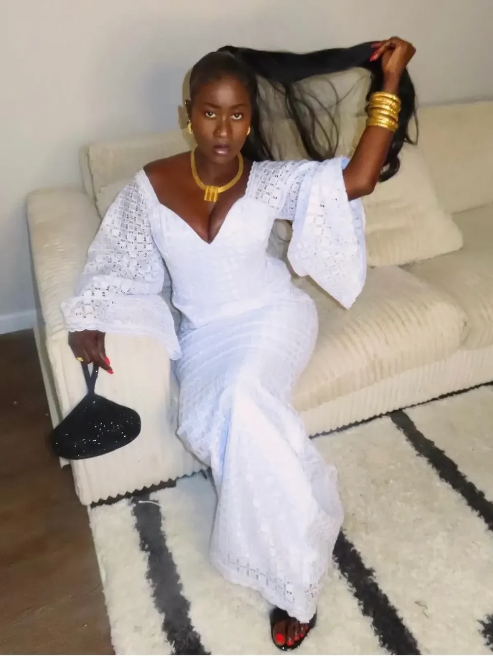 Adja in a white lace dress with gold jewelry