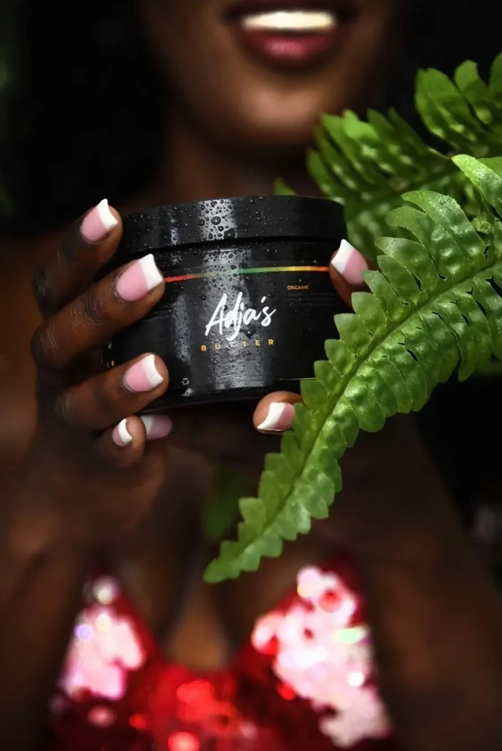 Adja’s shea butter jar held among green leaves