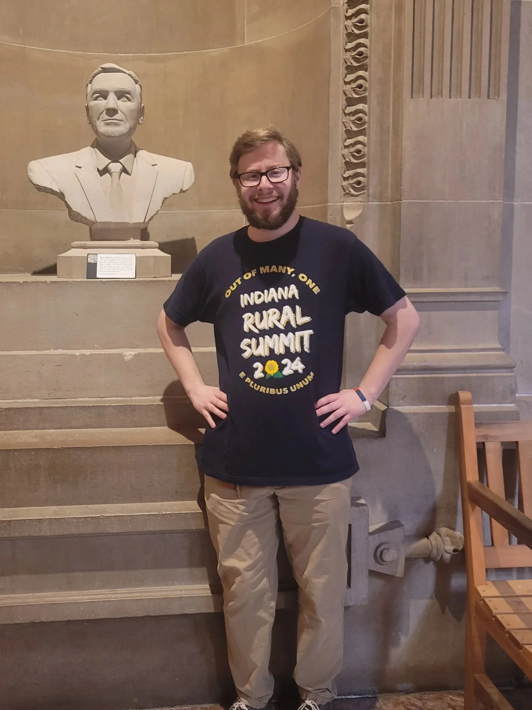 Photo of Kay Weidman, a white woman, wearing a dark brown top, sitting in a brown leather chair