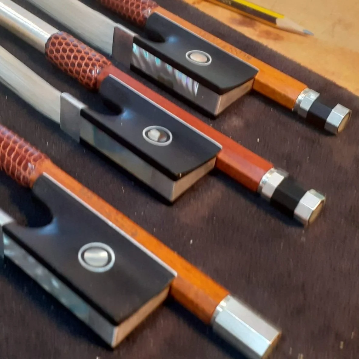 Three vintage wooden-handled knives with black and silver blades on a dark surface.